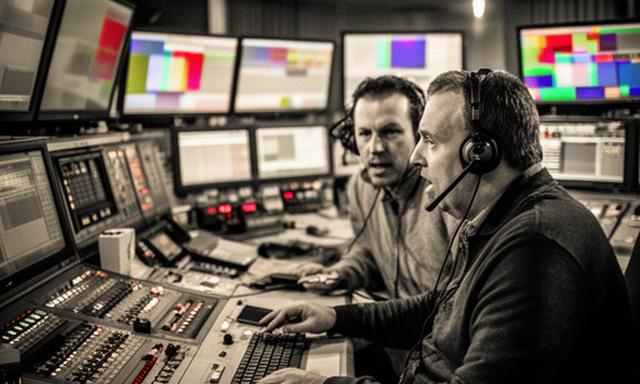 Regisseur en eindredacteur in een drukke talkshowregie met monitors